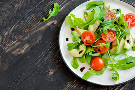 鳄梨和西红柿沙拉与芝麻菜和香醋在木, 复制空间。健康饮食素食素食夏日蔬菜沙拉食品概念