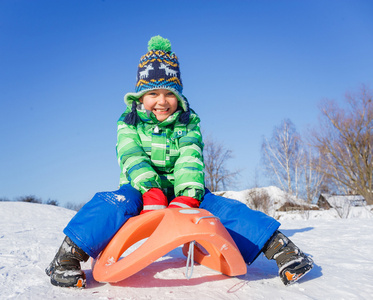 小男孩玩雪橇在冬季公园