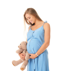 美丽的怀孕的妇女与玩具熊在白色背景