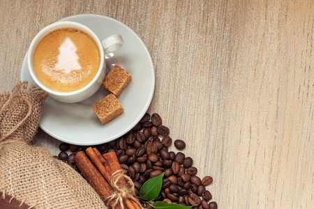 杯咖啡咖啡豆, 麻袋和肉桂在轻木背景上。与圣诞树标志在咖啡泡沫