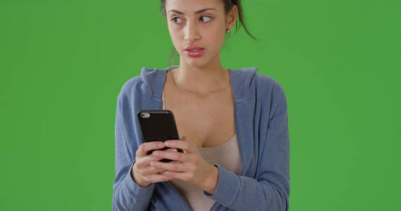 一个千禧年的拉丁女孩在绿色屏幕上给她的朋友发短信