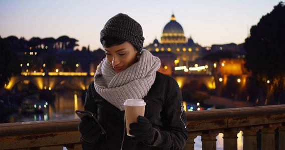 有吸引力的年轻黑人妇女与她的咖啡在罗马意大利使用智能手机