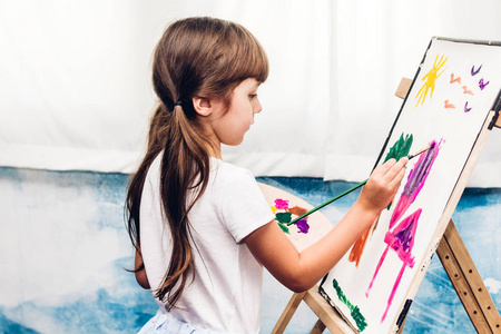 小女孩艺术家在画布上绘画与调色板和水彩颜料在家里照片