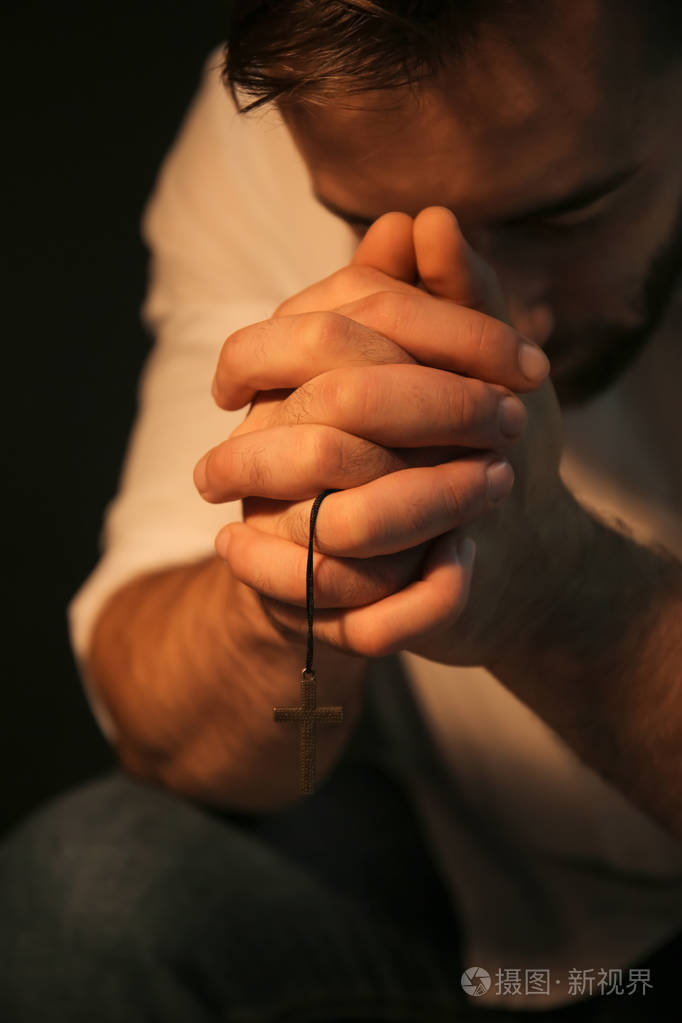 宗教年轻男子祈祷上帝在黑色背景, 特写镜头照片-正版商用图片09vc5a