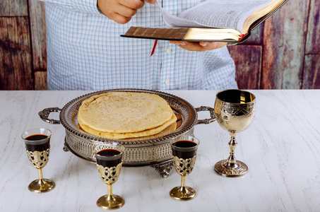 教堂的木桌上的圣餐仪式。圣餐杯红酒, 面包和阅读圣经