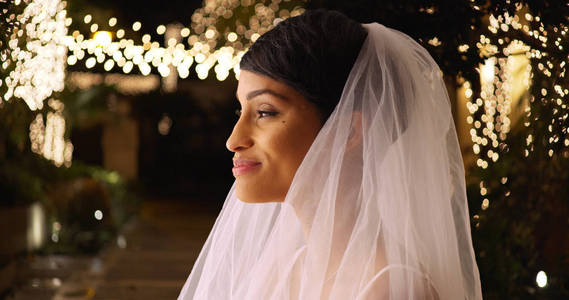可爱的新娘的简介在婚纱站在外面浪漫的场地在晚上