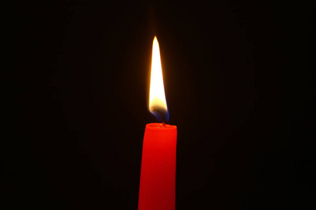 漂亮的蜡闪闪发光的红色蜡烛与大火灾的黑暗背景