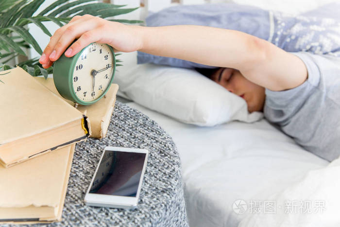 英俊的年轻男子睡在白色的床上用品