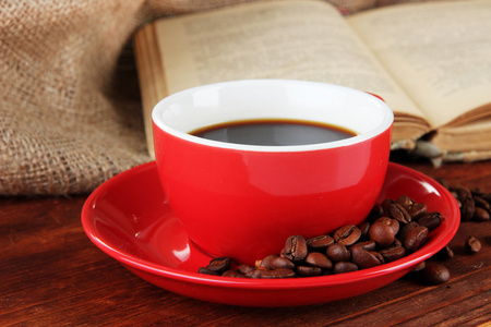 杯咖啡的咖啡豆和麻布背景上木制的桌子上的书