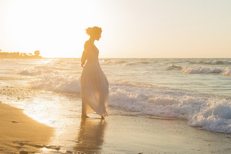 年轻的女人喜欢在黄昏时分朦朦胧胧的海滩上散步