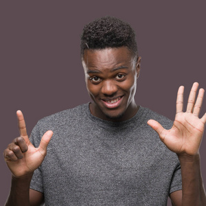 年轻的非洲裔美国人穿着灰色 t恤显示和指向七的手指, 而微笑着自信和快乐