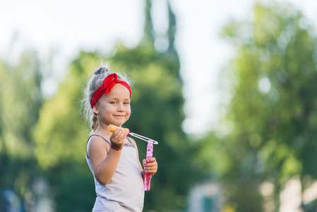 小女孩在公园里散步, 夏天吹肥皂泡。