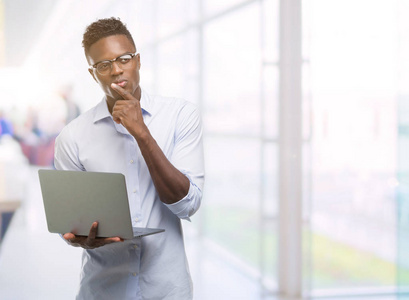 年轻的非洲裔美国商人使用电脑笔记本电脑严肃的面孔思考问题, 非常困惑的想法