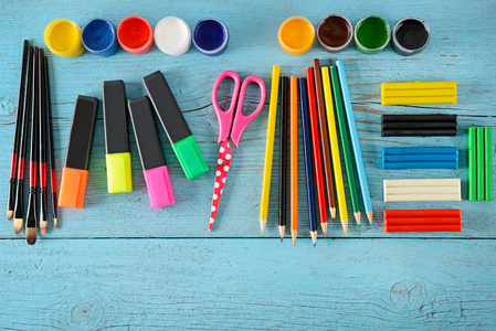 学校用品 剪刀, 油漆, 造型粘土, 标记, 铅笔 在蓝色的木质背景。顶部视图。复制空间