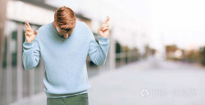 年轻的金发男人微笑着mischeviously同时发誓承诺欺骗交叉手指而作出