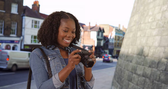 英国城市街道上漂亮的黑人女性用镜头微笑拍照