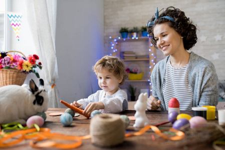 年轻的母亲和儿子的肖像在家里庆祝复活节和可爱的宠物兔玩
