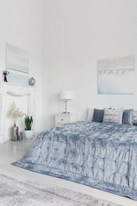 植物和灯旁边的蓝色床在白色最小的卧室内饰与海报。真实照片