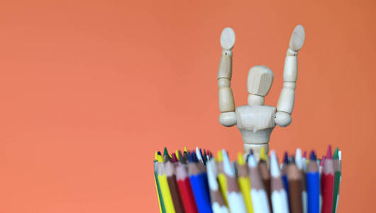 木头模特用五颜六色的铅笔。艺术用品创造力和教育的概念