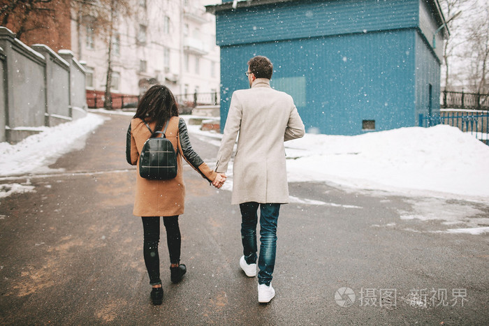 走在街上的年轻夫妇手牵手，在冬天
