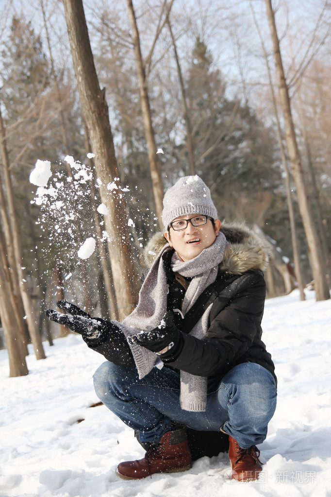 亚洲帅哥抛雪在空中花园里