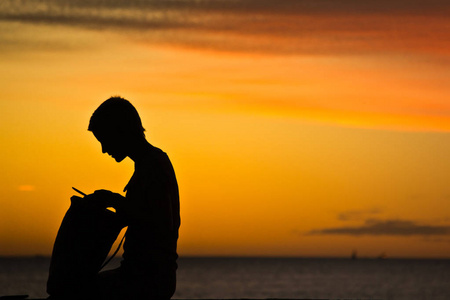 日落时在海滩上带着一个婴儿的家庭剪影