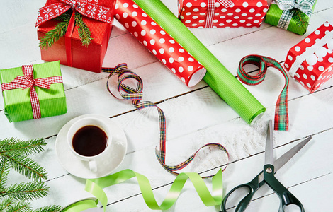 五颜六色的纸包装圣诞礼物和剪刀在一个白色的木桌上