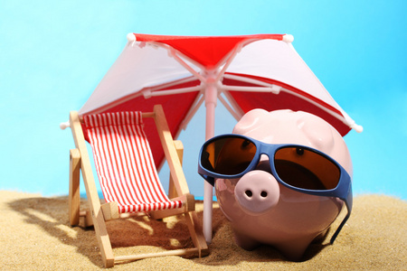 夏季储钱罐与站在沙滩椅旁边的红色和白色遮阳条件下砂的太阳镜