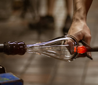 在佛蒙特州, 一位玻璃吹制艺术家用热成型工具将一泡玻璃制成容器