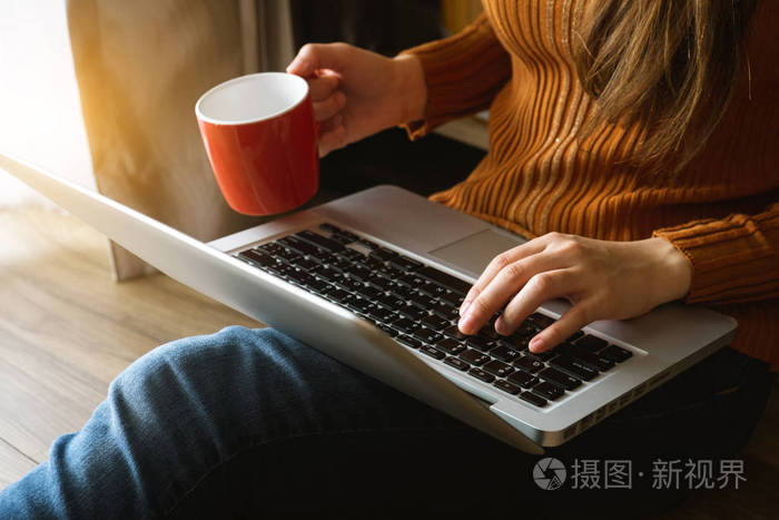 womman 使用笔记本电脑和打字在笔记本电脑和持有咖啡杯在咖啡厅