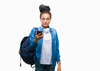 年轻的编织头发非洲裔美国学生女孩使用智能手机在孤立的背景与自信的表情在聪明的脸思考严重