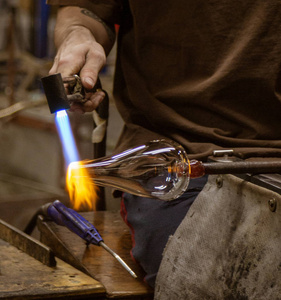 在佛蒙特州, 一位玻璃吹制艺术家用煤气火炬将一层玻璃组成成船只