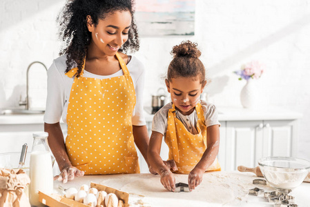 非洲裔美国母亲和女儿准备饼干与模具在厨房