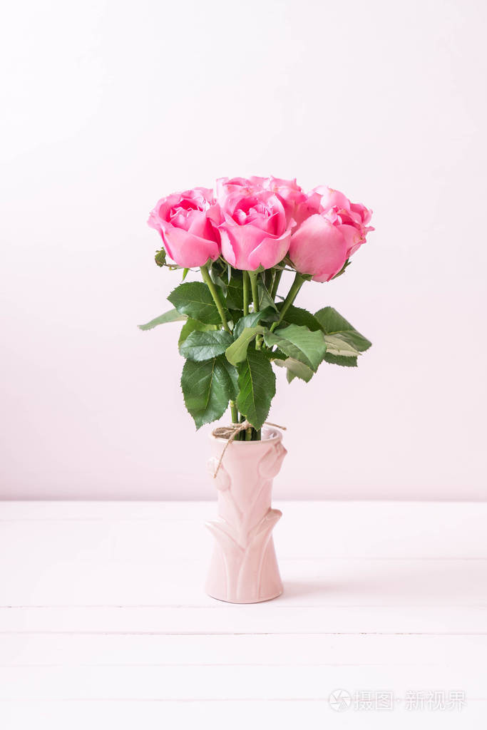 粉色的玫瑰插在花瓶里木背景