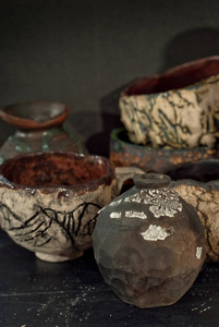 黑色木桌上的粘土陶器和陶瓷制品。家庭车间。手工制作的图纸和图案