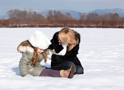 年轻的母亲和她的小女儿享受美丽的冬天一天户外活动