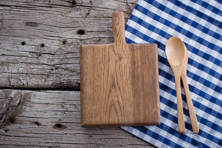 仿古餐桌蓝色格子桌布和木制裁剪板上的木制仿古餐桌背景.
