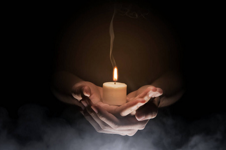 手拿着蜡烛在黑暗的背景。基督教 Pra
