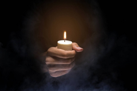 手拿着蜡烛在黑暗的背景.基督教 pra照片
