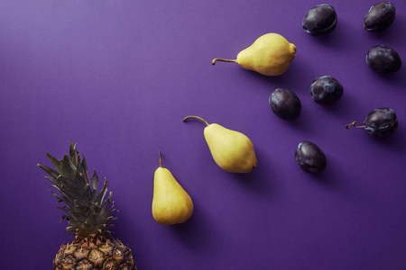 在紫罗兰表面上的梨, 李子和菠萝的顶部视图