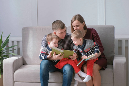 家里的妈妈, 爸爸和两个双胞胎兄弟在沙发上看书。家庭阅读时间