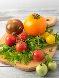 从草甸到餐桌的自制西红柿是不同颜色和大小的天然混合。在木板和勺子上呈现