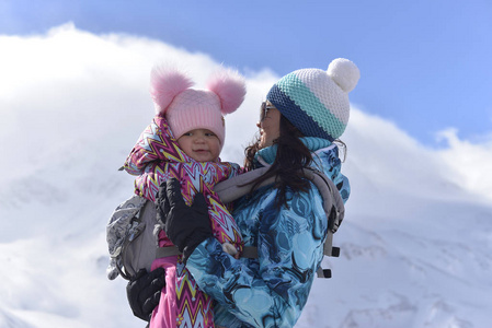 在一个阳光明媚的冬日里, 一位年轻的母亲和她的小女儿一起在山上旅行