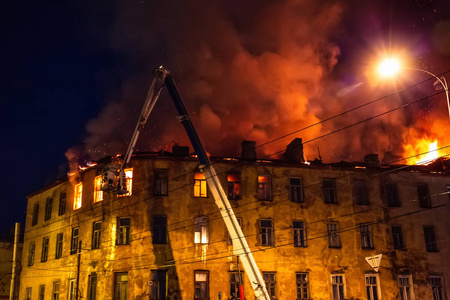 公寓楼屋顶的夜间火灾, 燃烧着巨大烟雾的房子, 火灾和事故悲剧