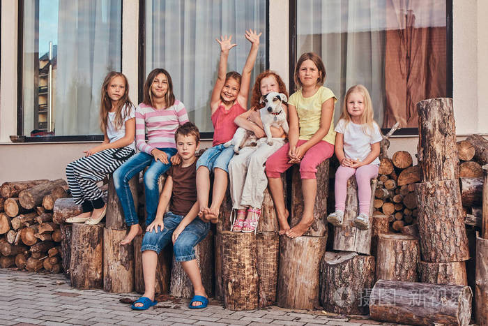 一群快乐的小朋友坐在后院的柴火上