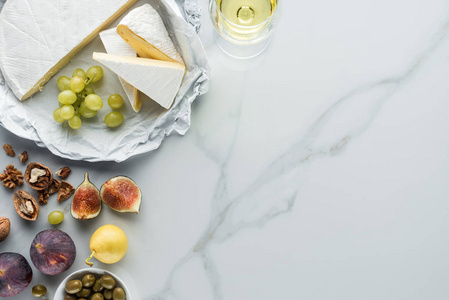 平躺与橄榄, 乳酪乳酪, 酒和果子安排在白色大理石表面