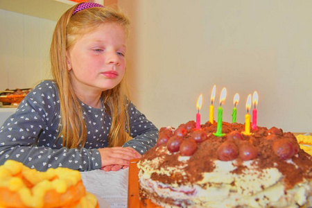 小女孩看着她的生日蛋糕。小女孩庆祝她的六个生日。生日蛋糕和小女孩