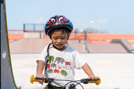 小男孩戴着头盔，骑着自行车。