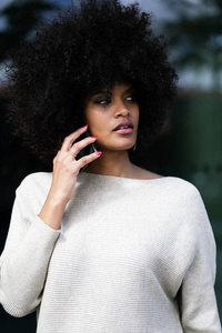 在街上使用手机的有吸引力的黑人妇女的肖像。商业女性概念
