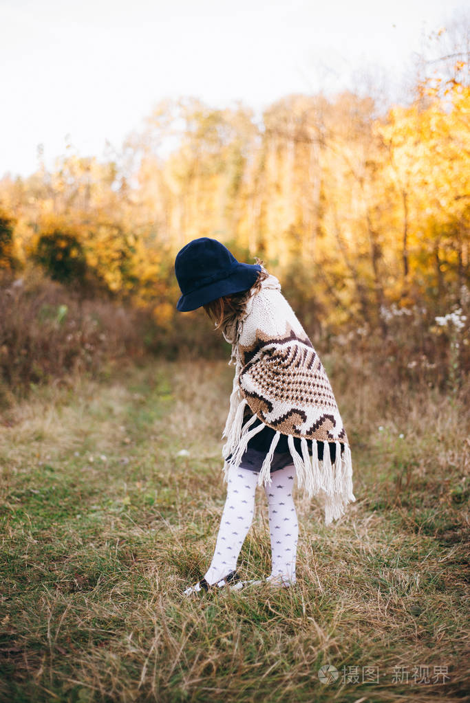 在秋天森林的披肩和帽子的女孩